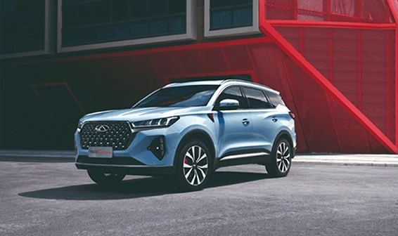 Chery SUV in silberblauer Farbe vor moderner Architektur mit rotem Akzent - sportliches Design mit elegantem Kühlergrill und zweifarbigen Felgen