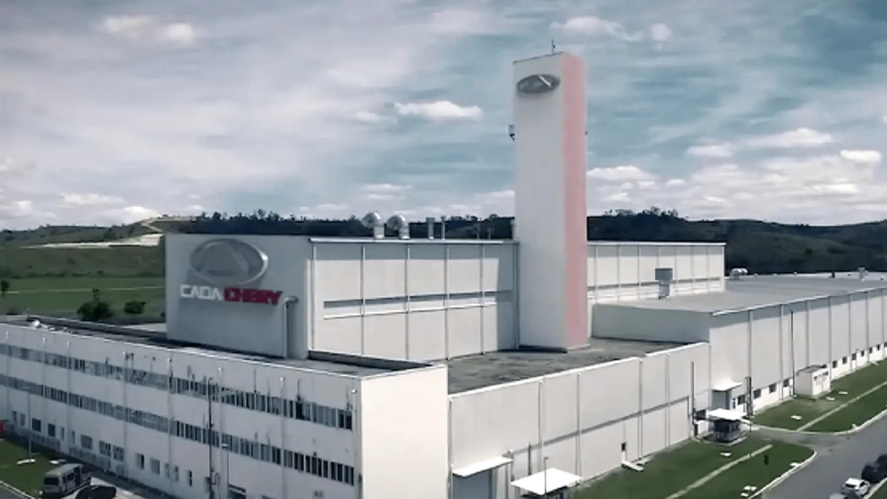 Luftaufnahme des modernen Chery Produktionswerks mit weißer Fassade und charakteristischem rosa Turm inmitten grüner Landschaft